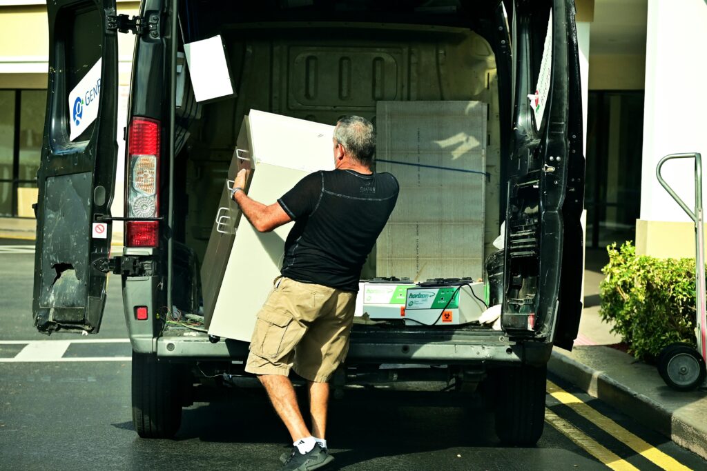 pexels-photo-5933476-5933476 Adult man loading furniture into an open van in a parking lot, daytime setting.
